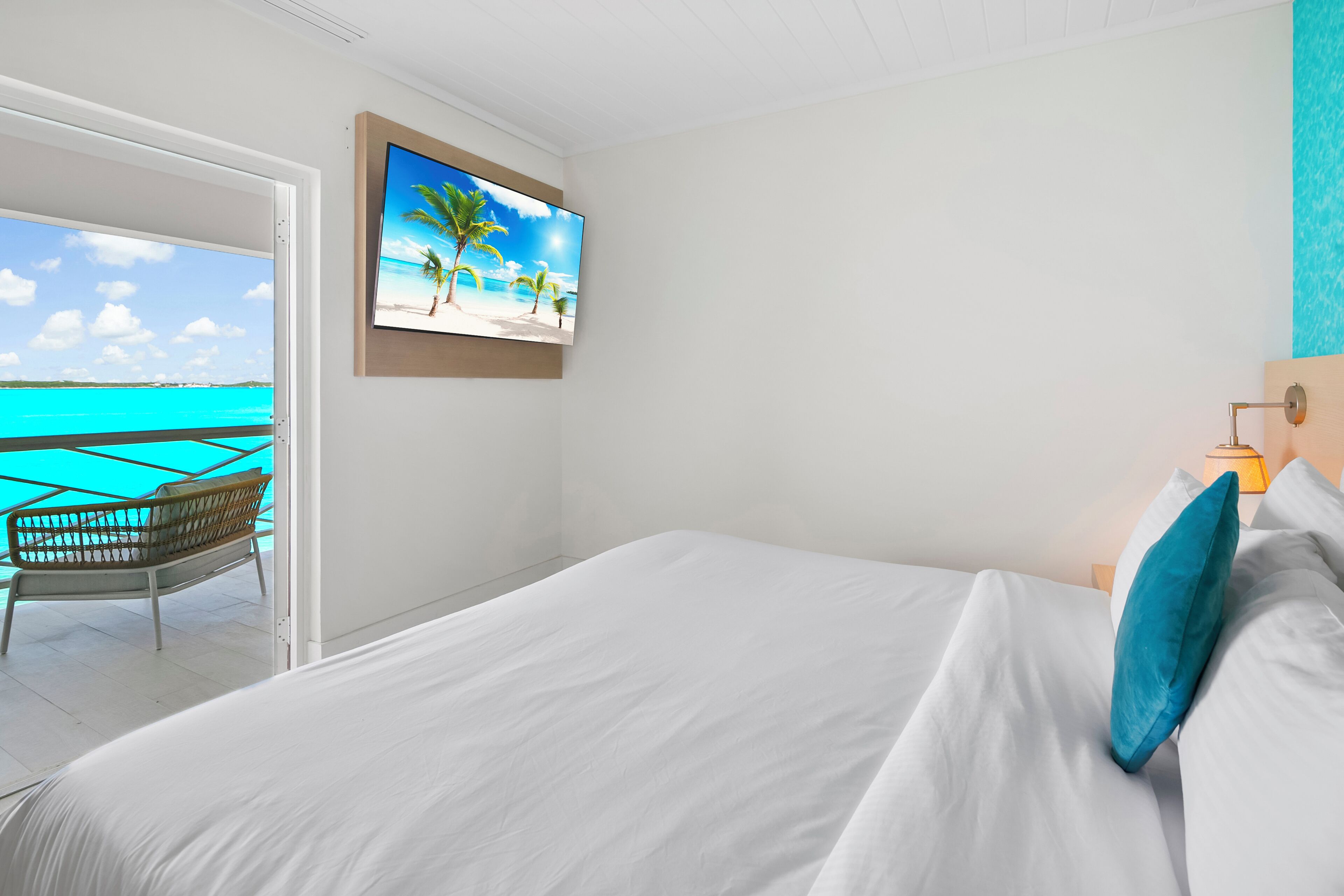 Ein Hotelzimmer mit Bett, Fernseher an der Wand und Blick auf den Ozean.