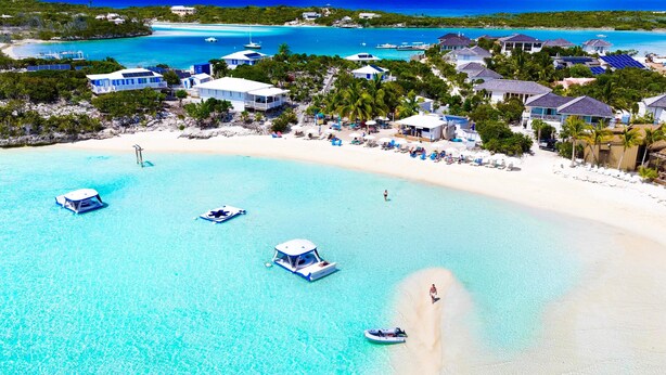 Un resort en la playa con aguas turquesas cristalinas, barcos y villas.