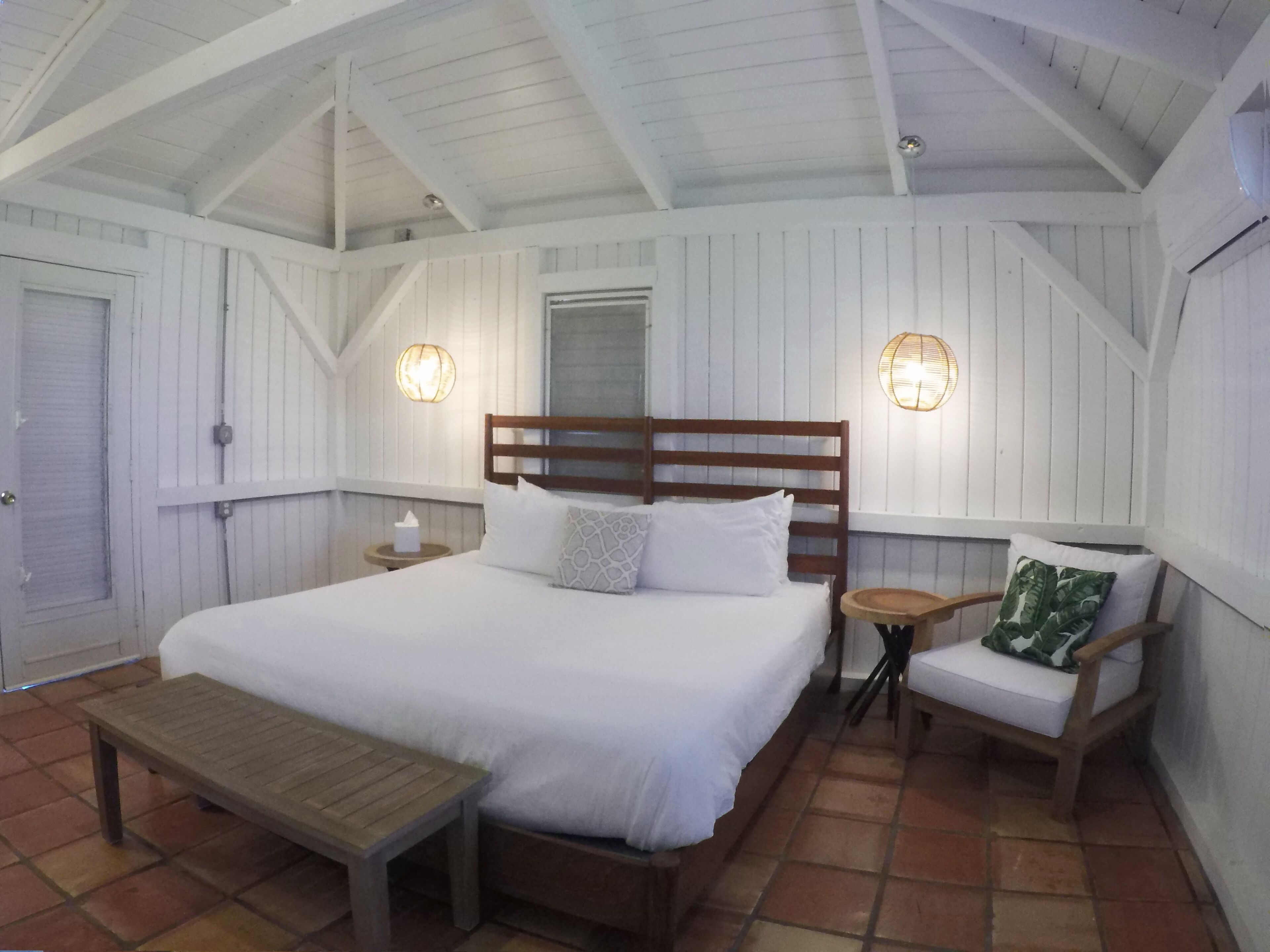 A bedroom with a wooden bed, a bench, two nightstands, and a window.