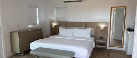 A bedroom with a bed, bench, dresser, bedside lamps, and a ceiling fan.