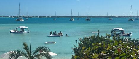 A beach with clear turquoise water, several boats, and people enjoying the area.