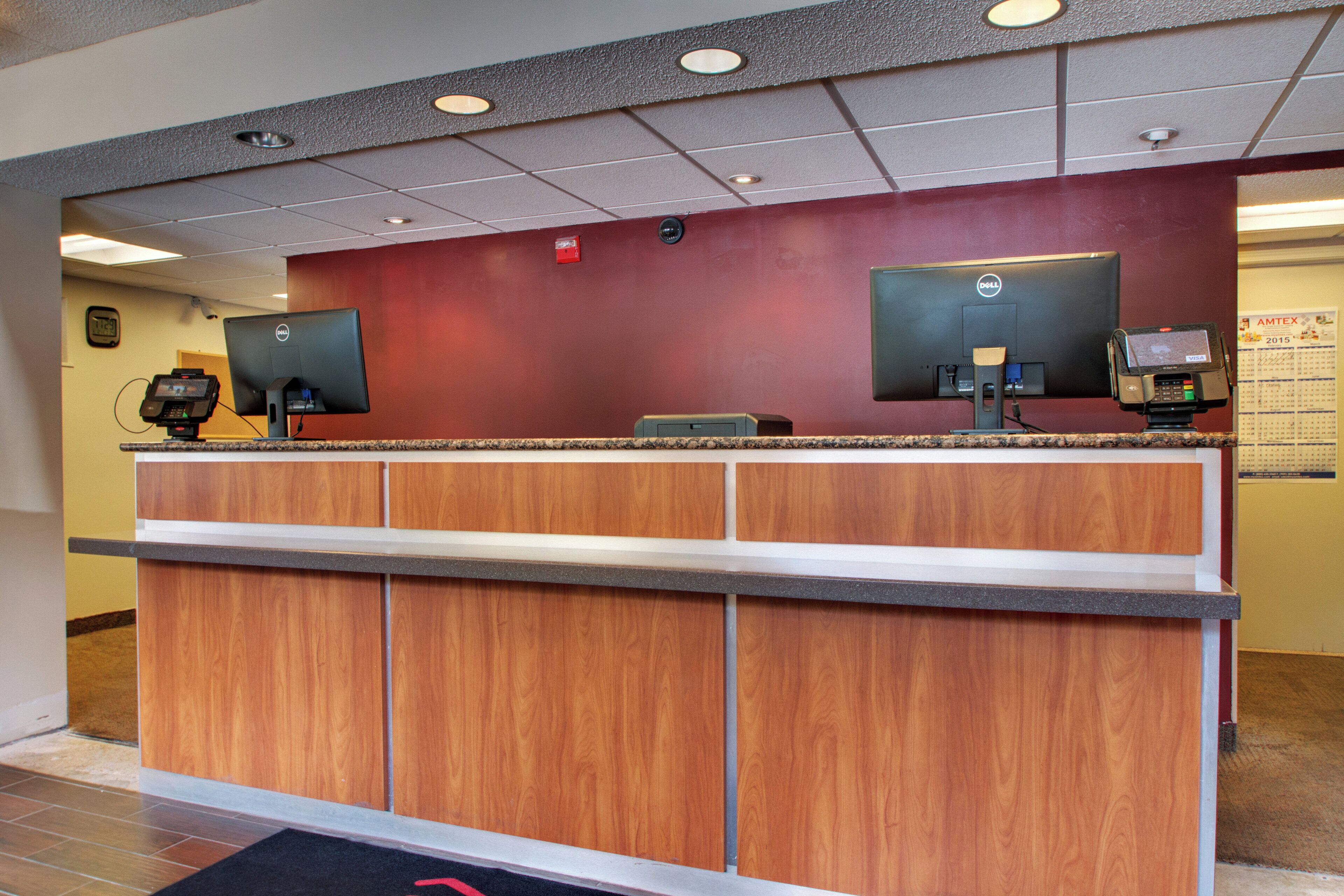 A reception desk with two computer monitors, a cash register, and a wall-mounted calendar.