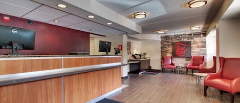 Zona de recepción de un hotel con un mostrador de madera, un detector de incendios, una computadora Dell y un letrero de Red Roof Inn.