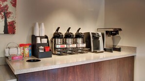 A coffee station with multiple coffee machines, a water dispenser, and a variety of coffee and creamer dispensers. - Red Roof Inn St Louis - Westport/ Maryland Heights (Maryland Heights)