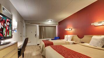 A hotel room with two beds, a desk with a computer, a TV, and a bathroom door.