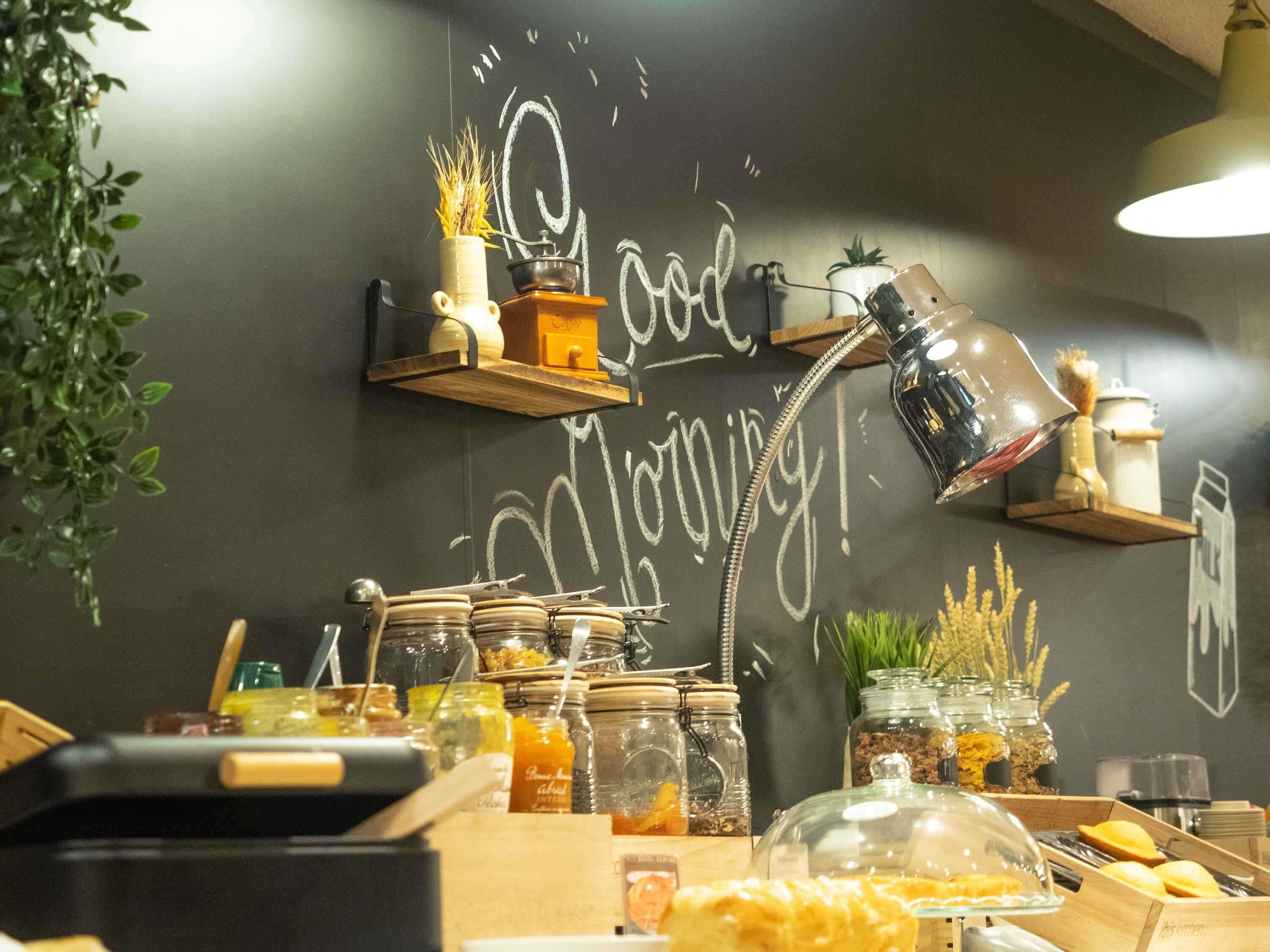 A kitchen area with a chalkboard wall, jars of food, and a coffee machine.