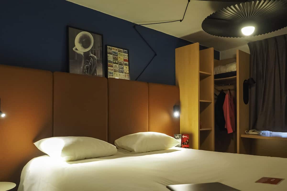 Una habitación de hotel con una cama, un ordenador portátil, un armario y un cartel en la pared.