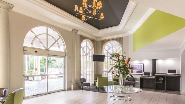 A spacious lobby with a glass coffee table, seating area, and a reception desk.