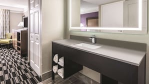 A modern bathroom with a large mirror, a sink, and a towel rack.