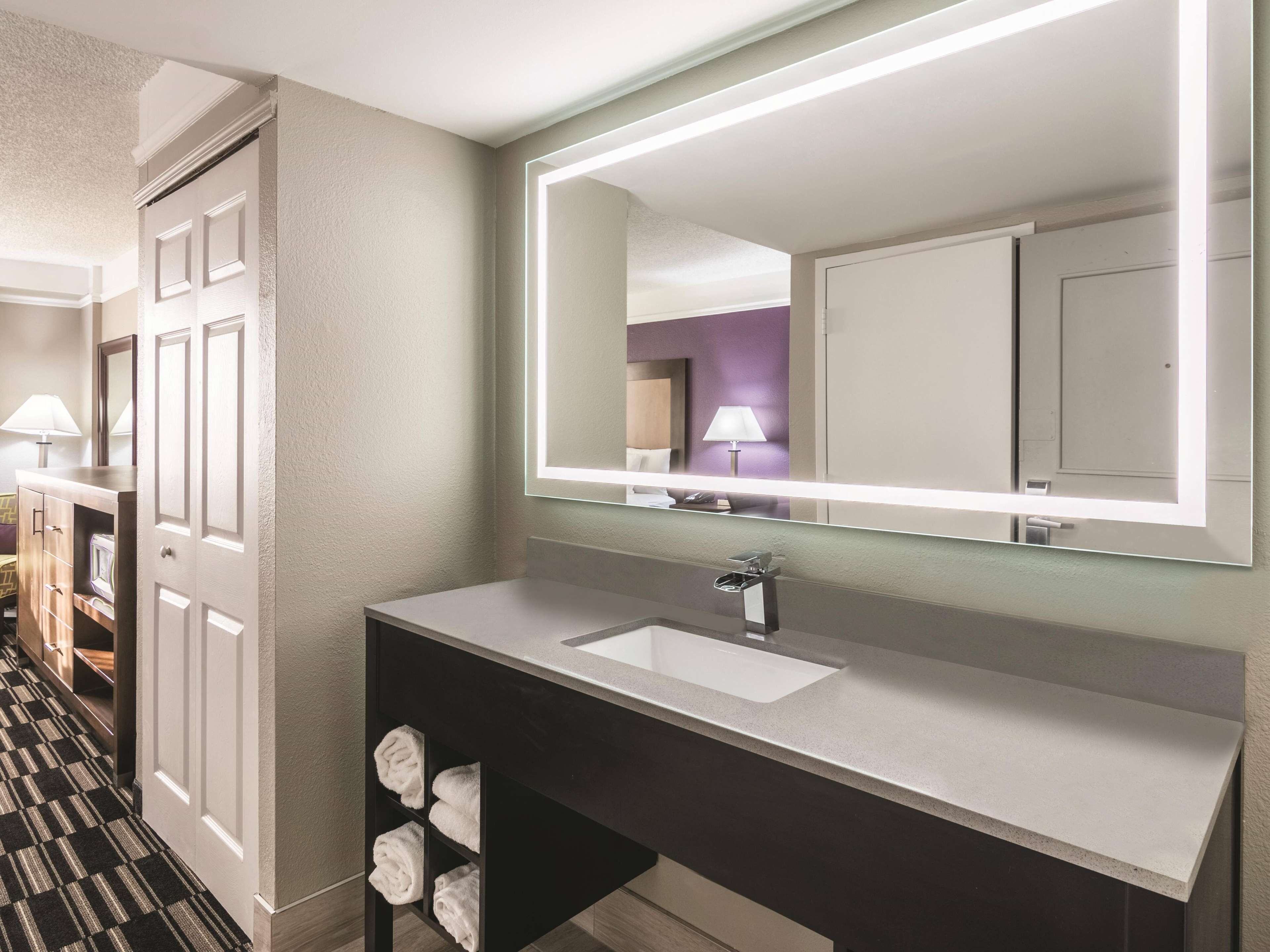 A modern bathroom with a large mirror, a sink, and a towel rack.