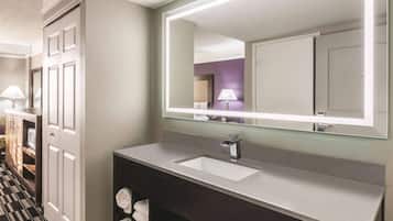 A modern bathroom with a large mirror, a sink, and a towel rack.
