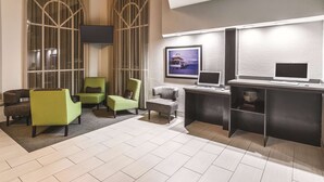 A modern lobby with a seating area, two computer stations, and a large window with curtains.