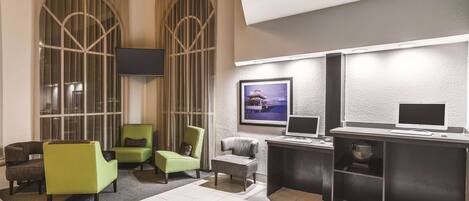 A modern lobby with a seating area, two computer stations, and a large window with curtains.