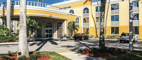 A hotel with a yellow facade, arched windows, and a covered entrance.
