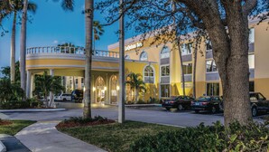 A hotel with a yellow facade, arched windows, and a covered entrance.