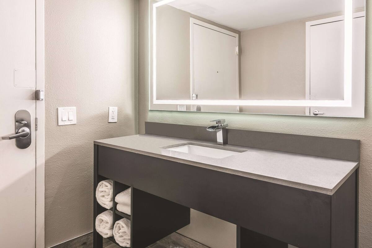 Un baño moderno con un espejo grande, un lavabo y un perchero para toallas.