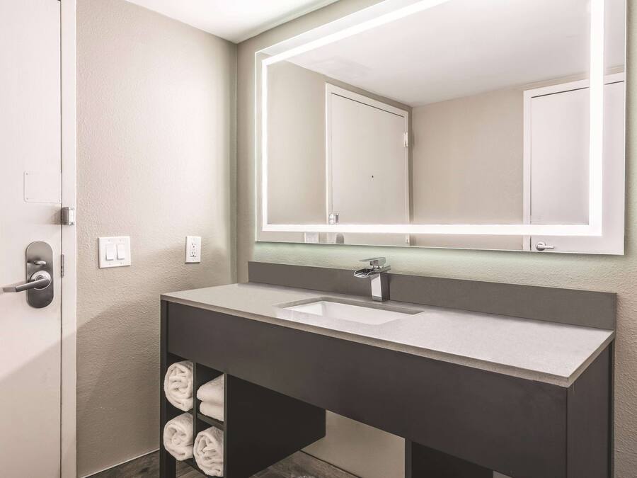 A modern bathroom with a large mirror, a sink, and a towel rack.