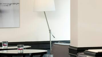 A room with round tables, a floor lamp, and a wall-mounted lamp.