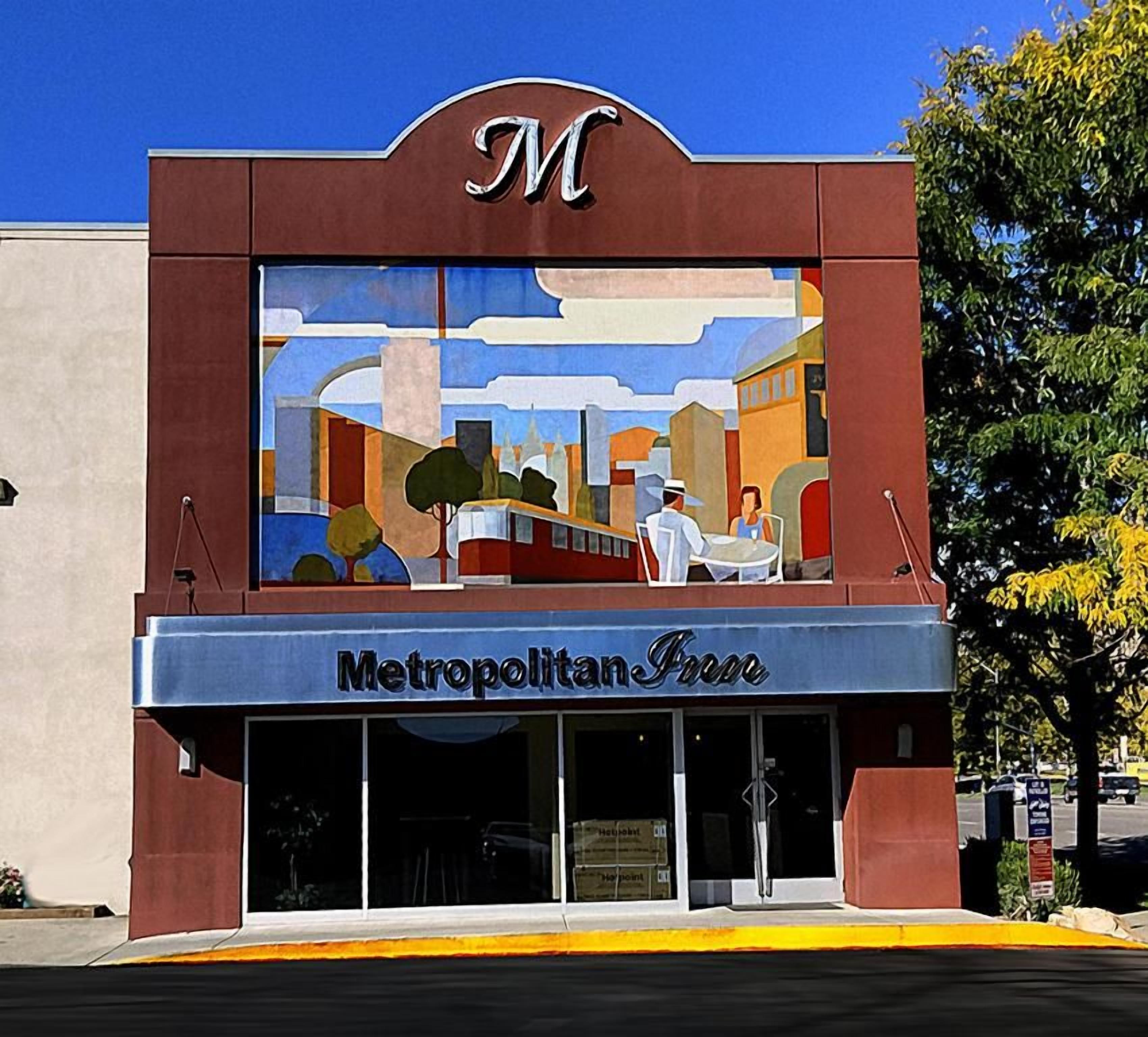 A building with a mural on the facade, a sign reading 'Metropolitan Free,' and a clear blue sky above.