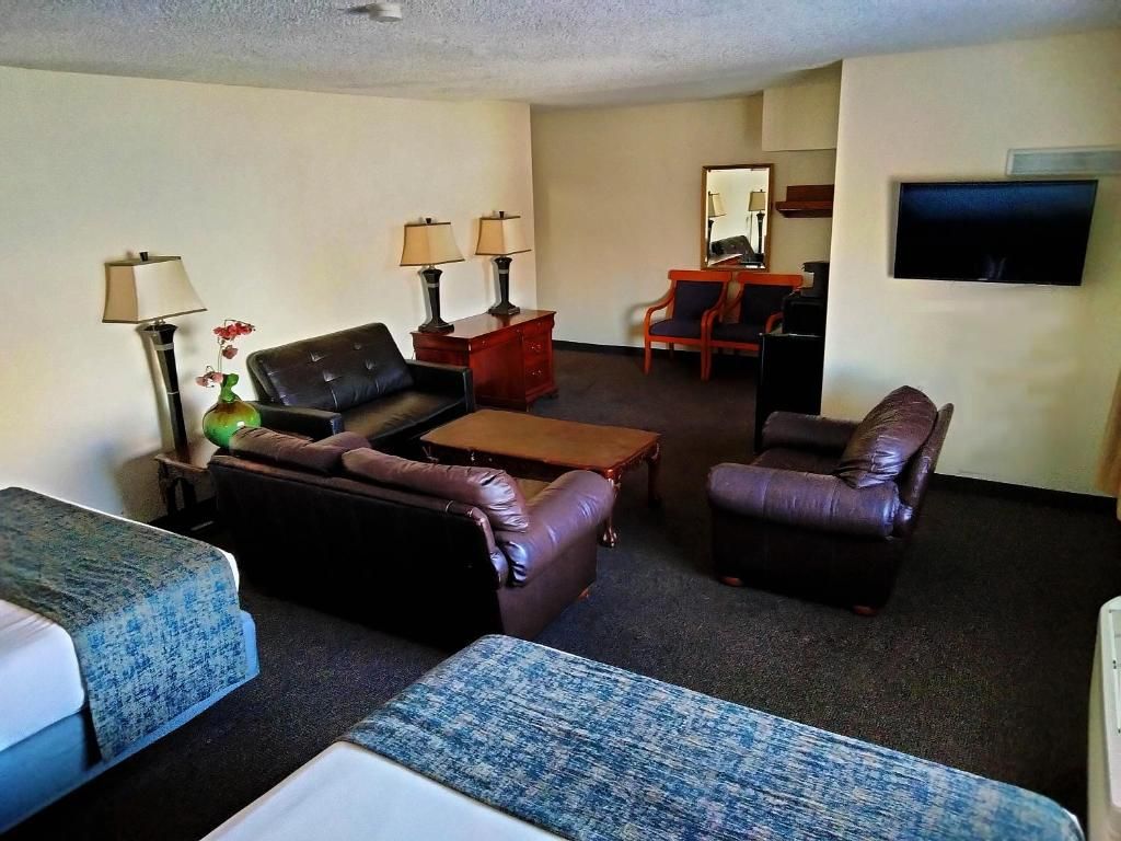 Una sala de estar amoblada con un sofá, sillones, una mesa de centro y un televisor.