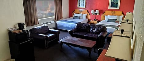 Una habitación de hotel con una cama, dos sofás, un escritorio y una lámpara.