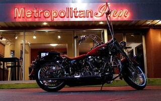 Una motocicleta estacionada frente a un edificio con un letrero de neón que dice "Metropolitan Inn".