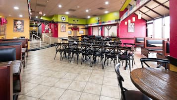 Ein Restaurant mit mehreren Tischen, Stühlen, einer Treppe zu einer erhöhten Ebene und verschiedenen Wanddekorationen.