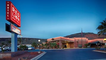 A Red Lion Hotel with a large sign, a parking lot, and a building with a flat roof and brick walls.