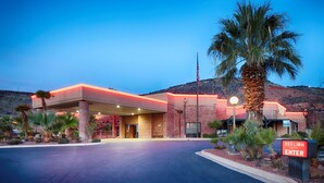 A Red Lion Hotel with a well-lit entrance, palm trees, and a mountainous backdrop. - Red Lion Hotel & Conference Center St. George, UT (St. George)
