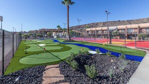 A golf course with a clear sky, palm trees, and a building in the background. - Red Lion Hotel & Conference Center St. George, UT (St. George)