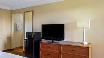 Una habitación de hotel con una cama, un aparador de madera, un televisor, un microondas y una lámpara.