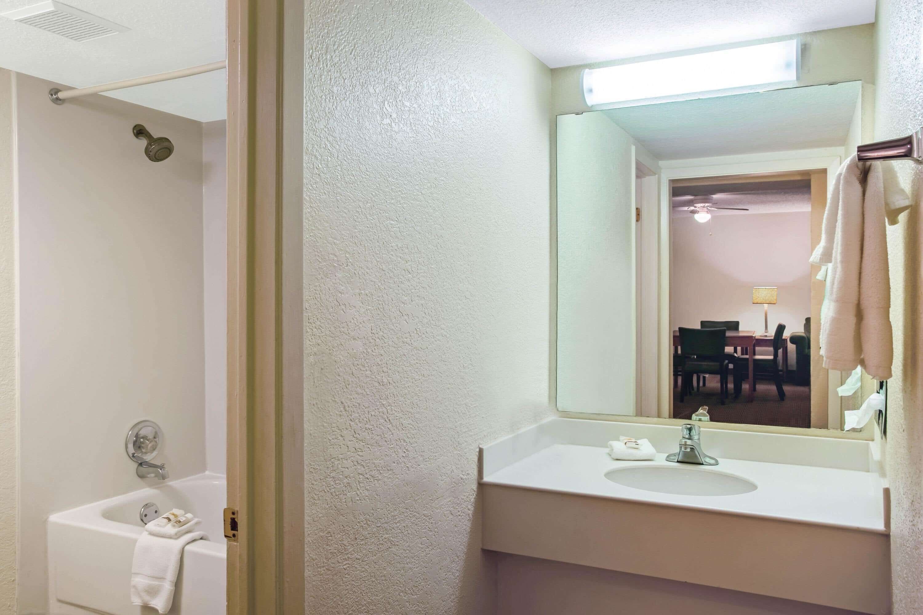 A bathroom with a bathtub, a sink, and a mirror.