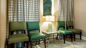 Een kamer met vier groene fauteuils, een tafeltje en een lamp.