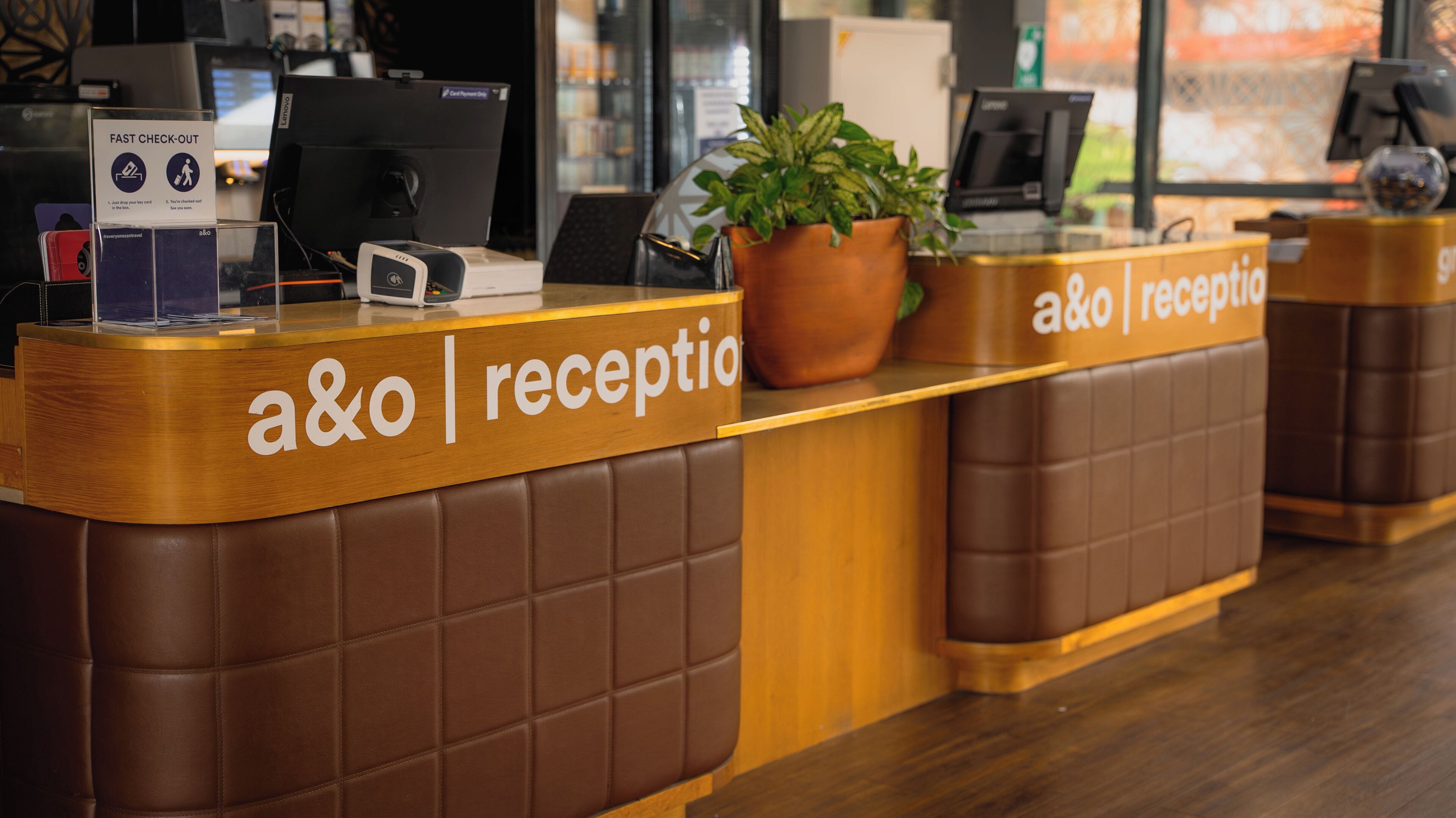 Ein Empfangstresen mit einem Schild mit der Aufschrift 'a&o reception' und einem Schild 'FAST CHECK-OUT'.