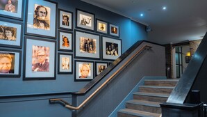 A staircase with a handrail and a wall adorned with framed photographs.