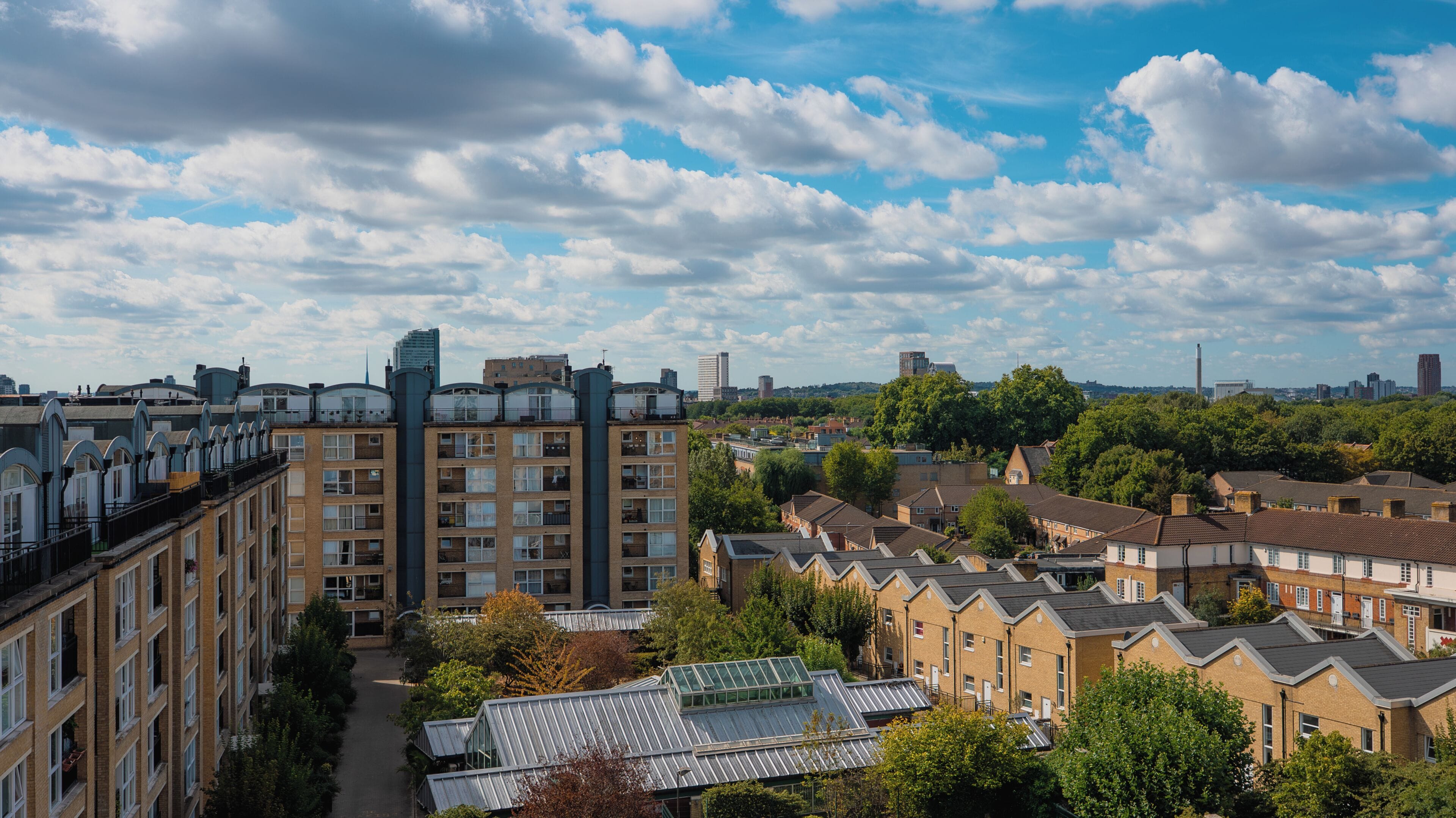 A residential area with terraced houses, a modern building, and a clear sky.