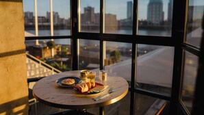 A table with breakfast items and a view of a cityscape through large windows.