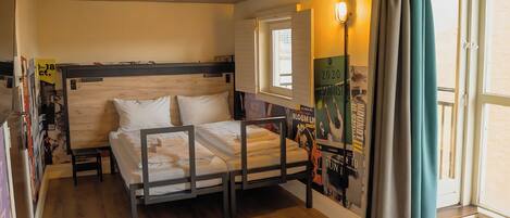 Ein Schlafzimmer mit einem Holzbett, einem Fenster, einer Tür und einem Poster an der Wand.