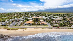 A coastal town with a beachfront, residential buildings, and a prominent hotel with a large roof and solar panels. - Maui Beach Vacation Club (Kihei)