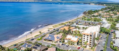 A coastal residential area with houses, a beach, and a mountain in the background.