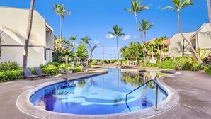 A swimming pool surrounded by palm trees and lounge chairs, with buildings in the background. - Maui Beach Vacation Club (Kihei)