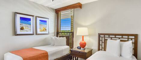 A hotel room with two beds, a ceiling fan, a window with blinds, and two framed pictures on the wall.