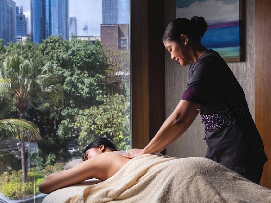 Een massagesessie in een ruimte met uitzicht op de stad door een groot raam.