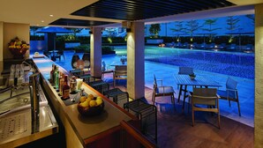 A bar area with a pool view, bar counter, seating, and outdoor umbrellas. - Makati Shangri-La, Manila (Makati)