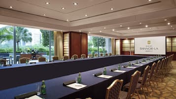 A conference room with a long table, chairs, and a projector screen displaying "Makati Shangri-La Manila".