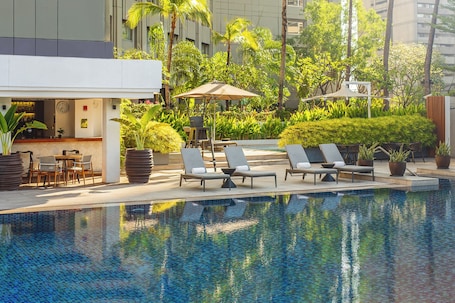 Una piscina al aire libre, sombrillas, sillones reclinables de piscina