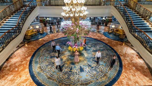 A grand lobby with a central floral arrangement, multiple staircases, and a patterned carpet. - Makati Shangri-La, Manila (Makati)