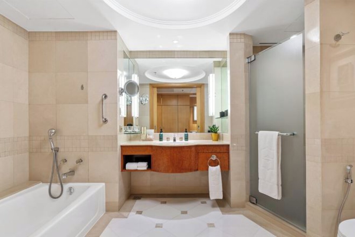 A modern bathroom with a bathtub, a shower, a vanity with a mirror, and a towel rack.