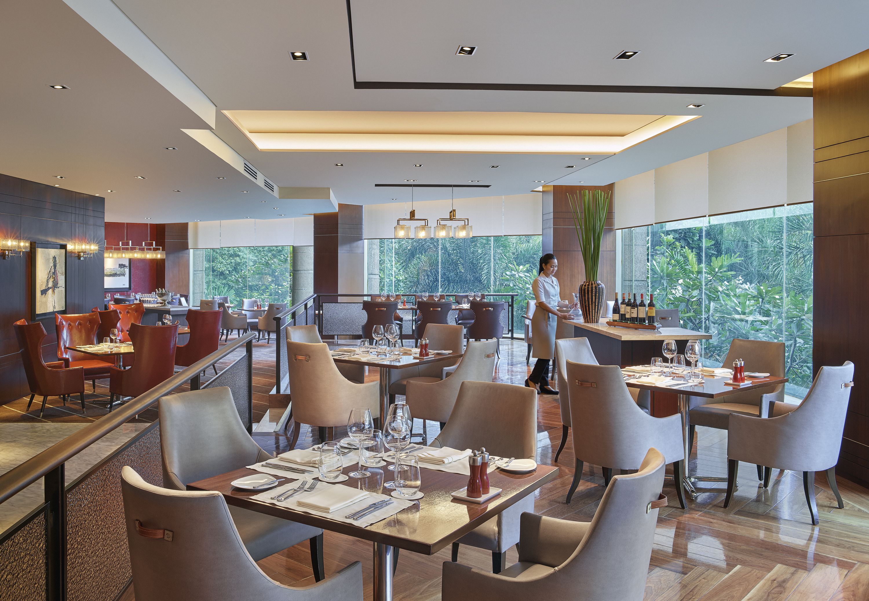 A modern restaurant with high ceilings, large windows, and a variety of seating arrangements.