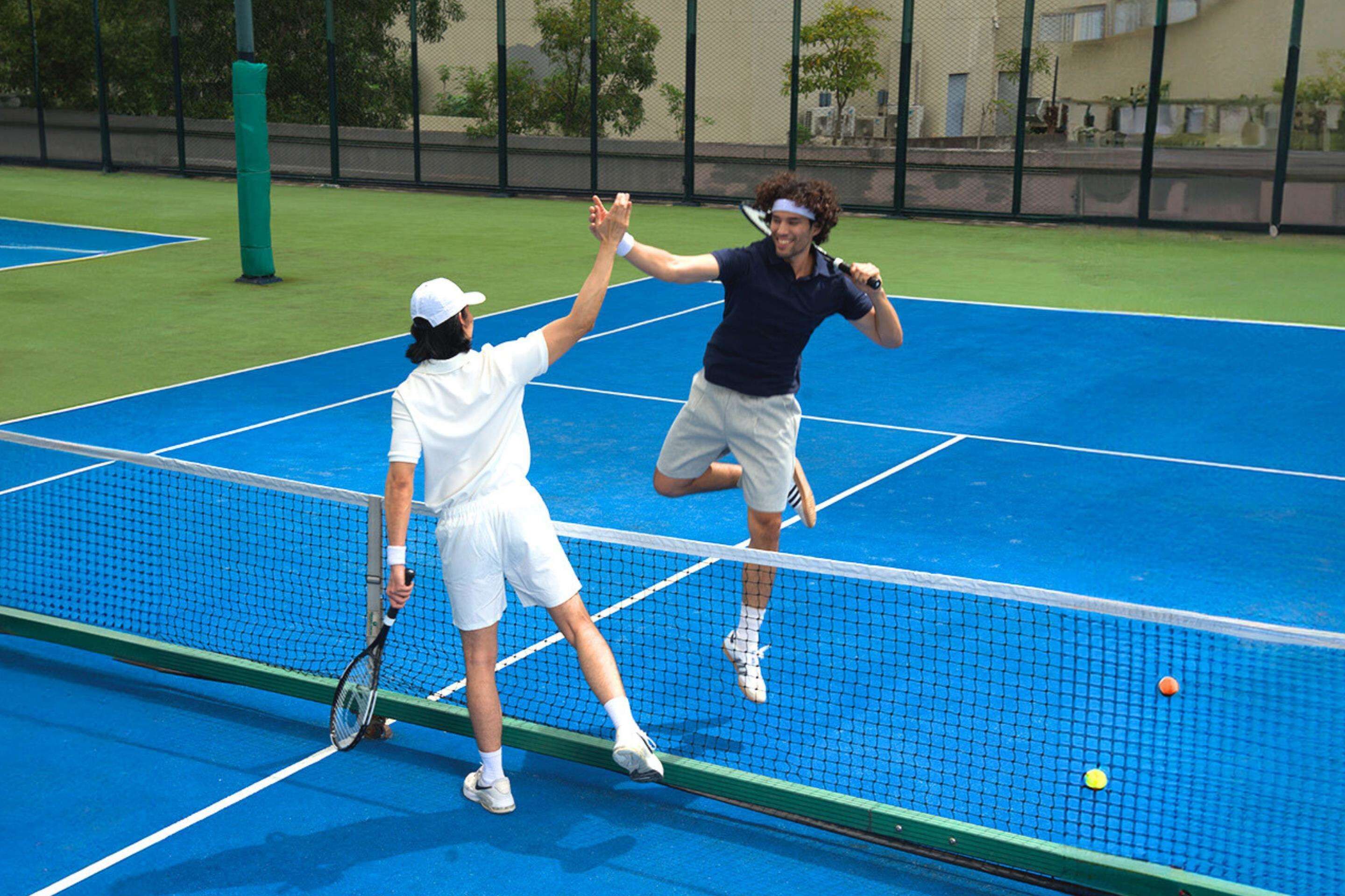 A tennis court with a net, two players, and a tennis ball.